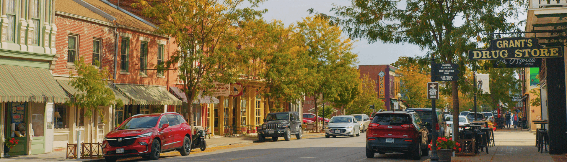 Quaint street lined with autumn trees and historic storefronts.