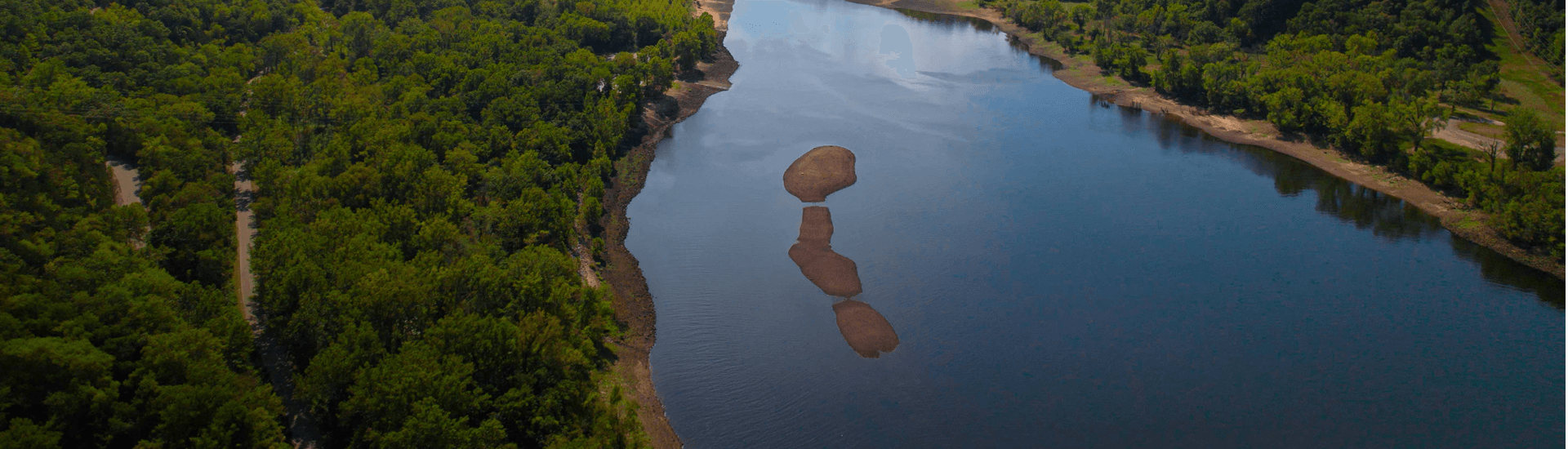 Aerial view of a river with rocky formations surrounded by lush green trees.